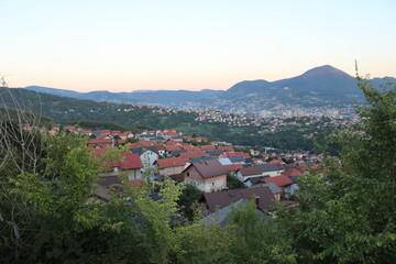 Obraz premium Serene village landscape with red roof houses in a green valley at sunset