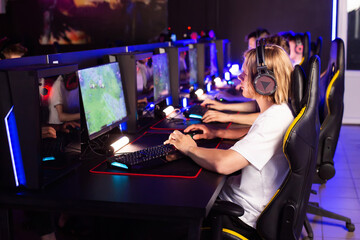 Team of gamers playing video game on PC at computer club, cyber sport tournament. E-sport championship. 5 players in headset communicate with each other over mic. Multiplayer online competition © HENADZY