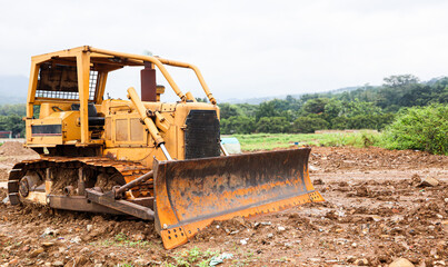 Old bulldozer parked on construction site with soil and dirt around, heavy machinery used for land clearing, road building and earthmoving work in rural landscape. © eza