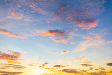 Fototapeta premium Golden Wispy Clouds at Sunset in Blue Twilight Sky,A panoramic view of vibrant orange and yellow wispy clouds scattered across a deep blue twilight sky during sunset. The soft, feathered cloud.