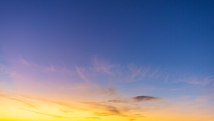 Golden Wispy Clouds at Sunset in Blue Twilight Sky,A panoramic view of vibrant orange and yellow...