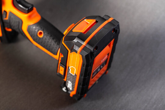 Cordless power drill battery and handle detail, highlighting robust design of tool with bright orange accents on black casing, showcasing essential component of portable electric device