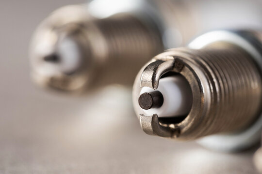 Detailed macro photograph of metallic automobile spark plugs, showing electrode tip, ground strap, and ceramic insulator, essential parts of combustion engine ignition