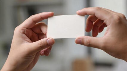 Fototapeta premium blank business card held in hands, office background, copy space