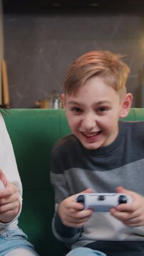 Young smilling woman and son playing video game together in moderm kitchen apartment enjoying indoor activity. Online entertainment and leisure activity concept. Slow motion.