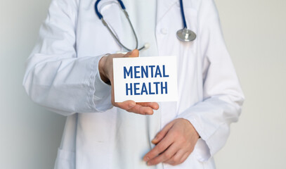 Doctor holding a card with MENTAL HEALTH text, representing psychological support, therapy, and healthcare professional assistance concept.