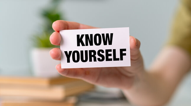 Hand holding a white card with KNOW YOURSELF text, representing self-discovery, psychology, and personal growth concept.