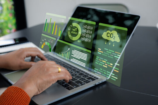 Businesswoman using laptop with virtual Net Zero and CO2 emission reduction dashboard. Concept of ESG sustainability, green energy management and carbon neutral business technology.