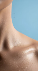 Fototapeta premium Close up of a person's neck and shoulder with water droplets glistening on the skin against a soft blue background