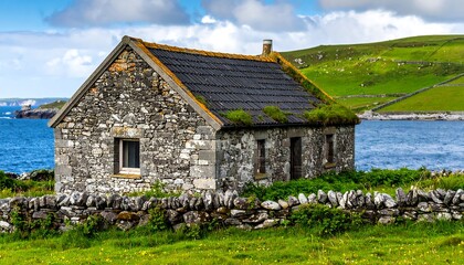 Obraz premium An aged stone cottage sits by a tranquil body of water, with rolling green hills in the background, under a vibrant sky