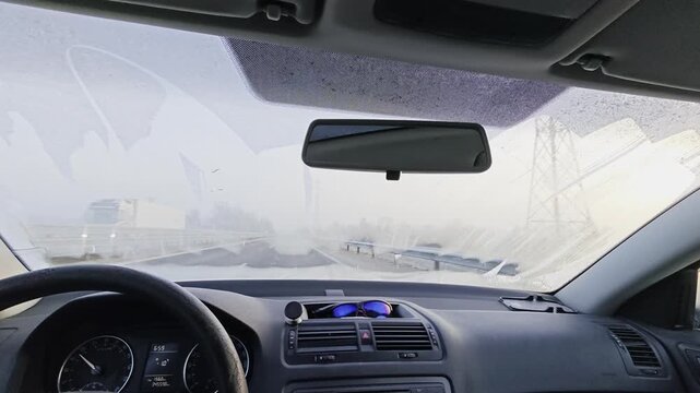 Frosted foggy  front windshield of passenger car during winter drive before interior heating clears the ice.