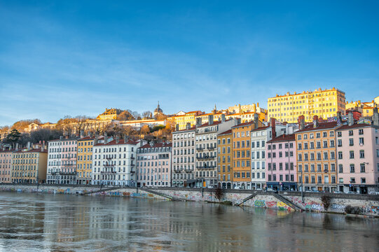 Lyon, france. December 27, 2023. Colorful historic buildings along the sa&ocirc;ne with croix-rousse hill and clear blue sky reflected in tranquil river waters &mdash; lyon panorama