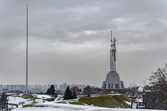 View of the towering Motherland Monument piercing the overcast sky, standing guard over the snow-dusted hills in Kyiv, Kyiv, Ukraine.