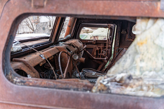 View of the skeletal remains of a vehicle, its rusty shell a stark contrast to the shattered glass, in Kyiv, Kyiv, Ukraine.
