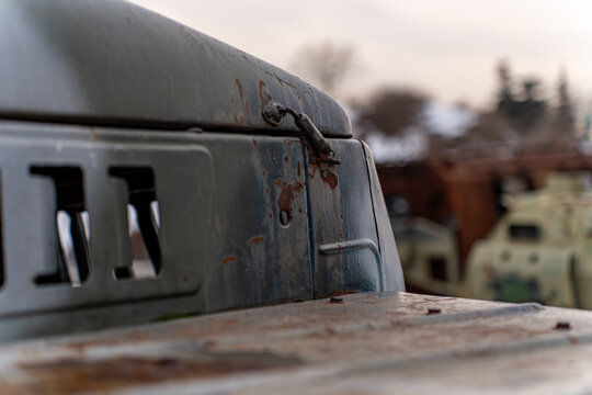 View of weathered metal surfaces and rusting hinges, reflecting a somber tone against the blurred backdrop of military vehicles, Kyiv, Kyiv, Ukraine.