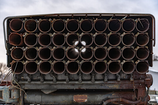 View of multiple launch rocket system with dark, circular tubes and weathered metal, standing stark against a muted sky, Kyiv, Kyiv, Ukraine.