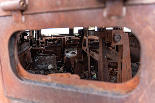 View of the interior of a rusted, derelict vehicle, a stark reminder of conflict, framed by a corroded opening, Kyiv, Kyiv, Ukraine.