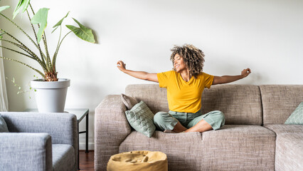 Happy afro american woman relaxing on the sofa at home - Smiling girl enjoying day off lying on the...