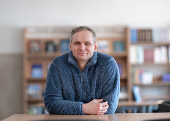 Casual Caucasian Male Portrait Of A Relaxed Man in Fleece Jacket Sitting at a Table in a Library © Mindaugas Dulinskas
