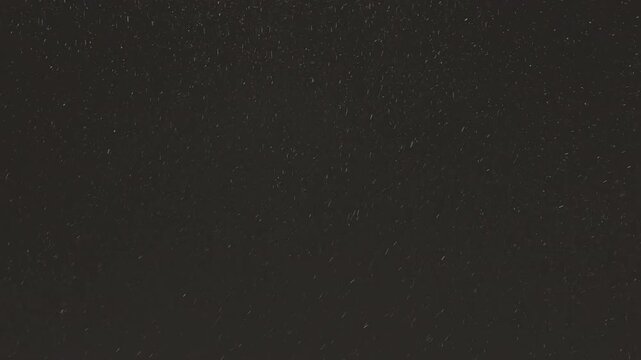 Street light illuminating falling snow during snowstorm at night. Realistic falling snow effect against a dark night sky, ideal for compositing winter scenes, creating a serene and magical atmosphere.