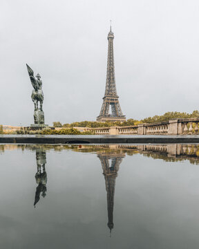 view of the Eiffel Tower and a statue reflecting in a pool of water, Paris, France.