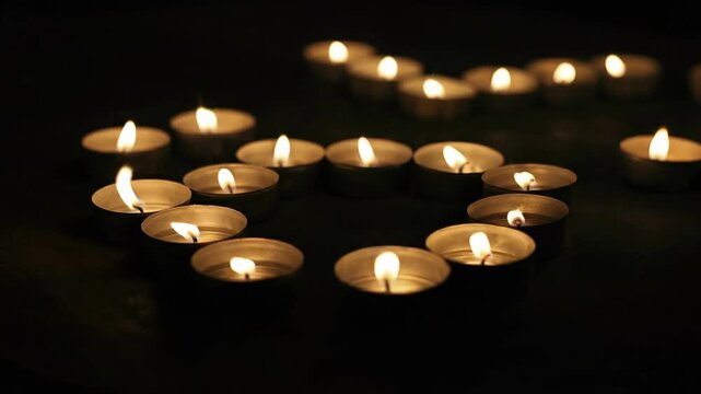 Gentle tea light candles flicker softly in the darkness, creating a warm and peaceful ambiance