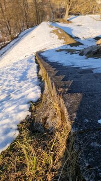 Lettland, Latgale &ndash; Rēzekne. Treppen zum Burgberg von Rēzekne im Fr&uuml;hling. Noch liegt Schnee, und das trockene Gras vom letzten Jahr ist zu sehen.