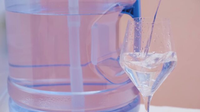 Close up of clean water pouring into glass with bottled water in background promoting health and daily hydration