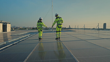 Obraz premium Male and female engineers inspecting rooftop solar panels on a modern building