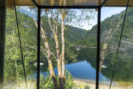 View of tranquil waters reflecting the lush mountain scenery through a window frame, capturing the essence of the Norwegian landscape, Bolstadoyri, Vestland, Norway.