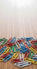 Fototapeta premium Colorful Paper Clips Scattered on Wooden Surface for Office Organization