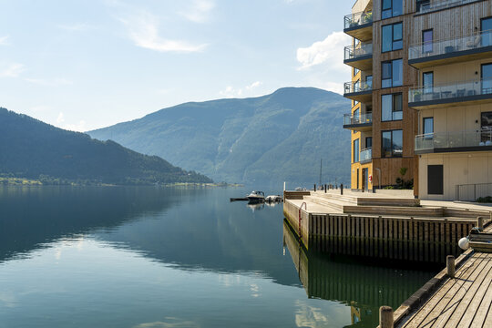 View of tranquil waters mirror the majestic mountains under a serene sky, with modern architecture adding a touch of elegance, Sogndal, Vestland, Norway.