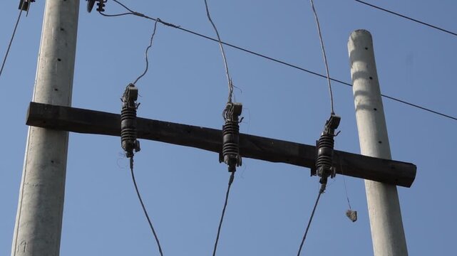 Electrical utility pole with insulators and power lines against blue sky