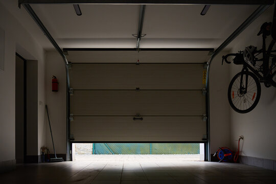 Interior view of residential garage with partially open sectional door, ceiling rails and bicycle