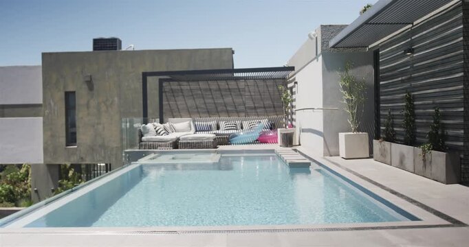 Sun and breeze creating ripples across turquoise pool and spa on rooftop, showcasing real estate