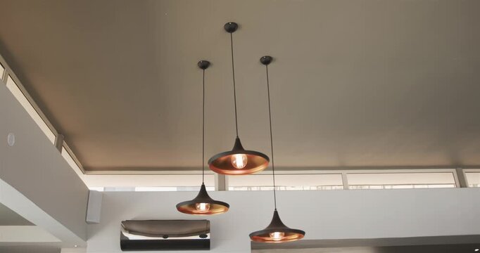 Pendant lamps swinging after minor disturbance in interior design, bulbs glowing, settling