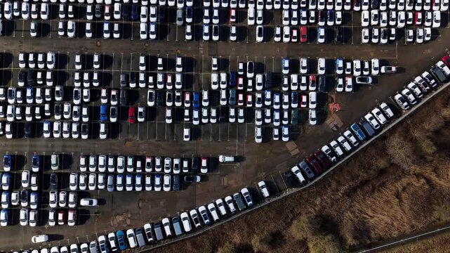 Aerial view of rows of parked cars in a storage facility, creating a geometric pattern of whites, blacks, reds, and blues, Grimsby, United Kingdom.