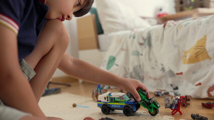 Young boy engaging in imaginative play with toy motorcycle and police car, creative storytelling, childhood fun, independent playtime, cozy bedroom setting © Marco