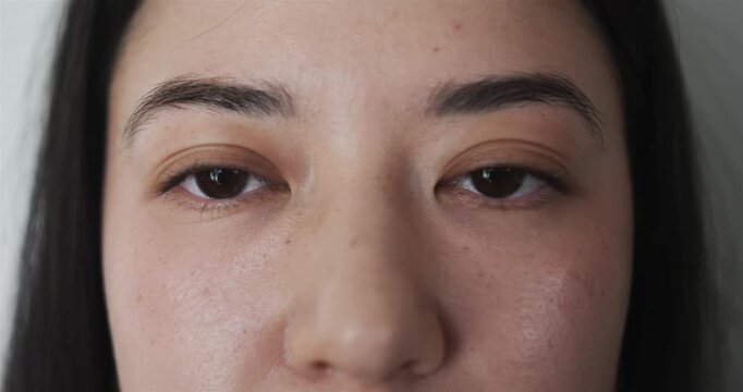 Teenager showing droopy eyelid, blinking slowly while presenting tiredness on plain wall background