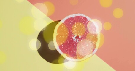 Displaying halved grapefruit with pink segments on two-tone backdrop, casting shadow and bokeh