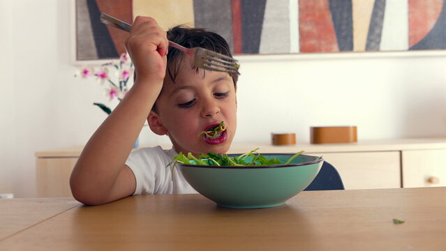 Young boy curiously inspecting forkful of arugula salad, pasta, and fresh vegetables at home dining table, uncertain about taste, childhood food experience, close-up shot