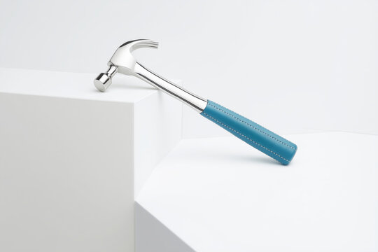 Martillo de plata con mango azul sobre bloques blancos, Mockup de martillo sobre pedestal blanco con espacio para a&ntilde;adir texto, Martillo moderno y minimalista para proyectos de dise&ntilde;o y arquitectura