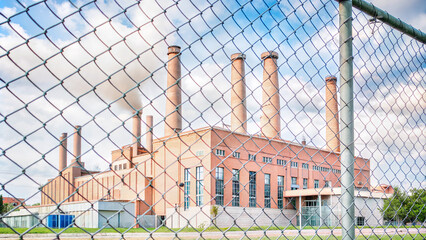 Industrial power plant with smokestacks behind chain-link fence  
