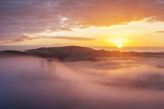 Misty Sunrise over Corfe Castle in springtime, Dorset, England, UK