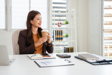 Smiling young asian businesswoman drink coffee enjoy morning in home office. Happy female small...