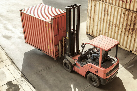 A forklift moves a shipping container at a warehouse site