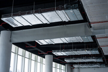 Naklejka premium Modern interior space with exposed ceiling structure featuring steel beams and ductwork