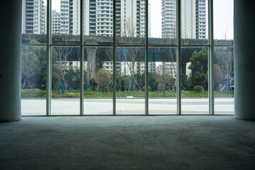 Empty interior space with floor-to-ceiling windows overlooking urban high-rise buildings and greenery © zhu difeng