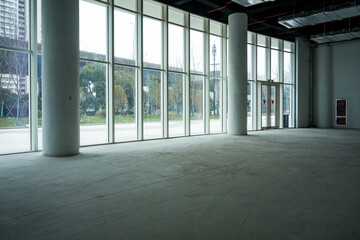 Naklejka premium Spacious modern office building lobby with floor-to-ceiling windows and concrete flooring