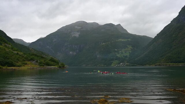 Mehrere Kajakfahrer in einem Fjord, umgeben von bewaldeten Bergen und Wolken, Geiranger, Geirangerfjord, Geiranger, Stranda, Romsdal, Norwegen, Europa